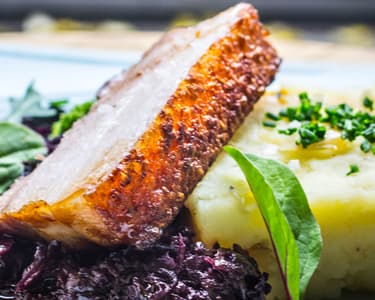 Sous vide pork belly with potato and cabbage, star anise red cabbage, and pan jus