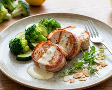 Bacon-wrapped turkey breast fillet on the grill, with buttery vegetables